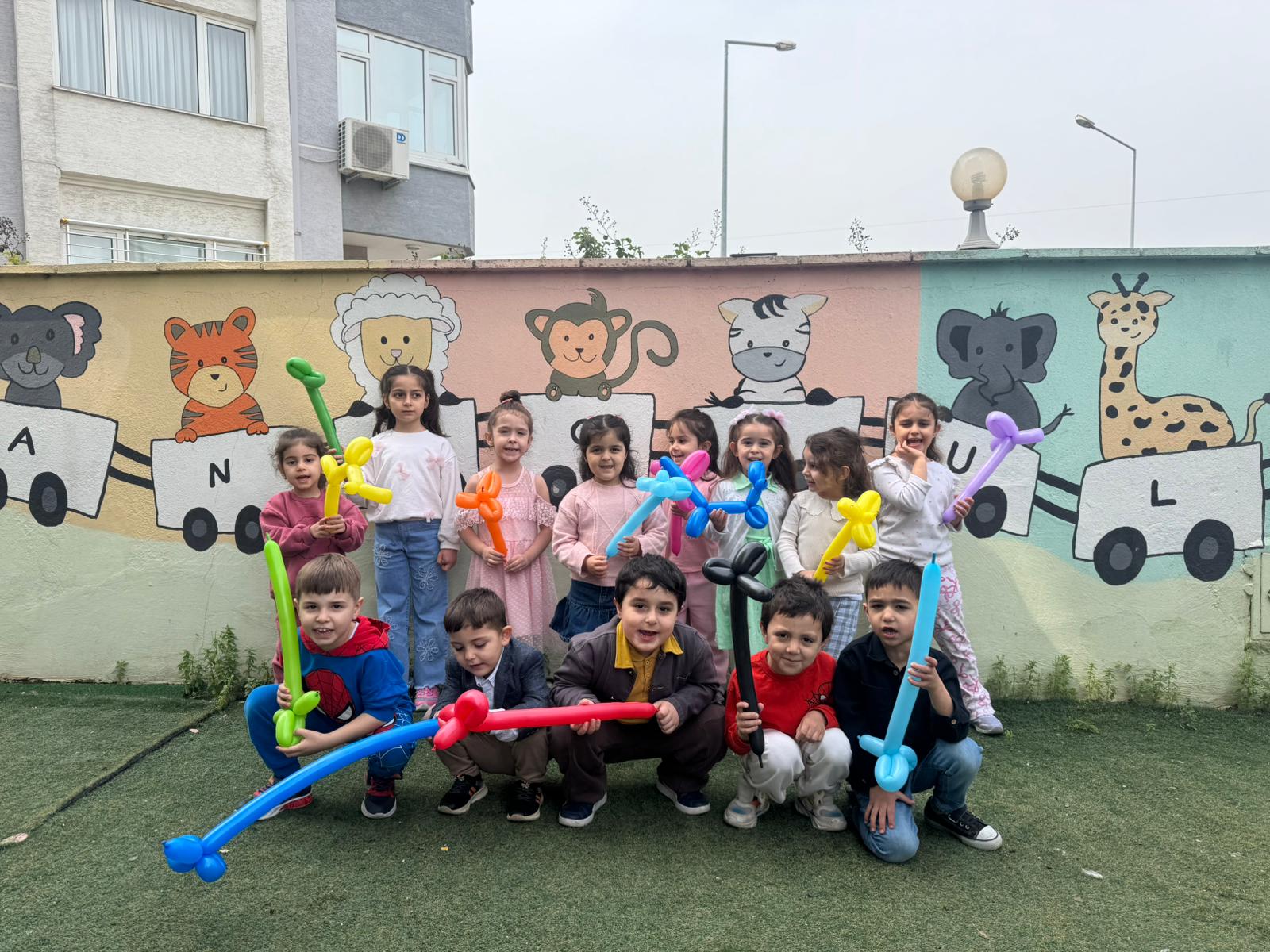 Bahçede balon figürleriyle poz veren öğrenciler